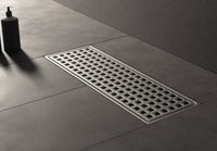 MaxxiBath G-T030FX stainless steel linear shower drain with a modern grid design, seamlessly integrated into a sleek, dark-tiled bathroom floor.